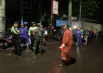 Petugas gabungan membersihkan sisa material sampah dan lumpur yang terjadi akibat meluapnya air sungai paron pasca hujan deras, Rabu (8/3/2023). Foto/Pusdalops BPBD Kota Batu