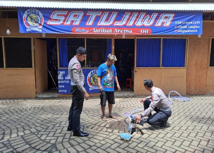 FT : Anggota Polres Malang membantu pedagang menguras genangan air diarea stadion Kanjuruhan. ( ist)