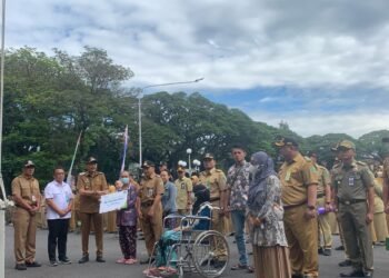 Ft: Pj Wali Kota Malang, Wahyu Hidayat menyerahkan secara simbolis kepesertaan dan manfaat program jamsostek oleh BPJS ketenagakerjaan di Halaman Depan Balai Kota Malang.(fat)