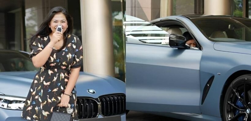 Liana Saputri tersenyum sambil memegang kunci BMW M850i di depan mobil mewah berwarna Frozen Barcelona Blue, menunjukkan kebahagiaan setelah menerima kendaraan edisi langka.