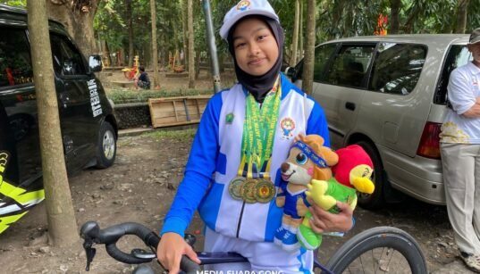 Aila Zahra atlet Malang sabet 3 medali 2 emas 1 perunggu diatas sepeda dan memegang boneka