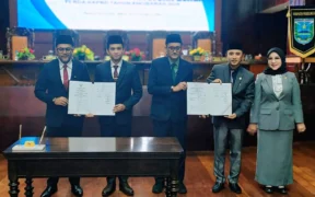 Pemerintah Kabupaten (Pemkab) Probolinggo bersama DPRD resmi mengesahkan Rancangan Peraturan Daerah (Raperda) tentang Anggaran Pendapatan dan Belanja Daerah (APBD) 2026 menjadi Peraturan Daerah (Perda). Pengesahan dilakukan dalam rapat paripurna yang digelar di Gedung DPRD Kabupaten Probolinggo, Sabtu (29/11/2025) pagi. Penetapan APBD ini menjadi tonggak penting karena menentukan arah pembangunan dan pelayanan publik di Kabupaten Probolinggo sepanjang tahun anggaran 2026. Sinergi DPRD dan Pemkab dalam Pengesahan APBD Rapat paripurna dipimpin Wakil Ketua DPRD Kabupaten Probolinggo, Didik Humaidi. Dalam kesempatan itu, ia menegaskan bahwa pengesahan APBD adalah wujud sinergi dan kesepahaman antara legislatif dan eksekutif. “Ini adalah komitmen bersama agar program pembangunan dan layanan masyarakat dapat terlaksana secara maksimal pada tahun anggaran 2026,” ujar Didik. Penandatanganan persetujuan bersama dilakukan untuk memberikan dasar legalitas sekaligus memastikan arah kebijakan pembangunan daerah berjalan sesuai rencana. Detail Pendapatan Daerah: Optimalkan PAD dan Transfer Dalam Perda APBD 2026 yang disahkan, pendapatan daerah ditetapkan sebesar Rp2.334.142.893.365. Pendapatan ini terdiri dari: PAD: Rp446.038.434.876 Pendapatan Transfer: Rp1.888.104.458.489 PAD yang cukup signifikan mencerminkan upaya pemerintah daerah meningkatkan kemandirian fiskal melalui optimalisasi pajak, retribusi, dan pengelolaan aset daerah. Sementara pendapatan transfer tetap menjadi penopang terbesar bagi anggaran daerah. Alokasi Belanja Daerah dan Penutupan Defisit Total belanja daerah tahun 2026 tercatat sebesar Rp2.406.142.893.365, yang dialokasikan pada empat sektor utama: Belanja Operasional: Rp1.788.064.887.752,48 Belanja Modal: Rp142.164.070.812,52 Belanja Tidak Terduga: Rp10 miliar Belanja Transfer: Rp465.913.934.800 Dari perhitungan pendapatan dan belanja, APBD 2026 mengalami defisit Rp72 miliar. Defisit ini ditutup melalui Penerimaan Pembiayaan Rp72 miliar, sehingga struktur APBD tetap seimbang dan aman secara fiskal. Respons Bupati Probolinggo: APBD untuk Masyarakat Bupati Probolinggo, dr. Mohamad Haris atau Gus Haris, menyampaikan rasa syukur dan apresiasinya terhadap DPRD yang telah bekerja sama selama proses pembahasan. “Alhamdulillah, Perda APBD 2026 telah disahkan. Terima kasih kepada pimpinan dan seluruh anggota DPRD atas kerja sama dan masukan konstruktif,” ujar Gus Haris. Ia menegaskan bahwa pemerintah daerah akan memperhatikan seluruh catatan dan rekomendasi fraksi untuk memastikan setiap program betul-betul memberi manfaat bagi masyarakat. “Kami berkomitmen agar program yang berjalan nantinya benar-benar dirasakan manfaatnya oleh masyarakat,” tegasnya. Makna Strategis APBD 2026 Pengesahan APBD 2026 dinilai sangat strategis, bukan hanya sebagai dokumen anggaran, tetapi sebagai instrumen untuk: mempercepat pembangunan infrastruktur, meningkatkan layanan publik, memperkuat sektor pendidikan, kesehatan, dan ekonomi, serta memastikan pemerataan pembangunan antarwilayah. Sinergi legislatif dan eksekutif yang terbangun juga menjadi modal penting untuk mewujudkan visi Kabupaten Probolinggo yang maju dan sejahtera.